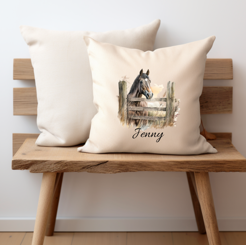 A cream cushion cover with a chestnut horse looking over a gate printed on one side with a personalised name option,the cushion cover has a zip opening and is displayed on a small bench,the pet printing company