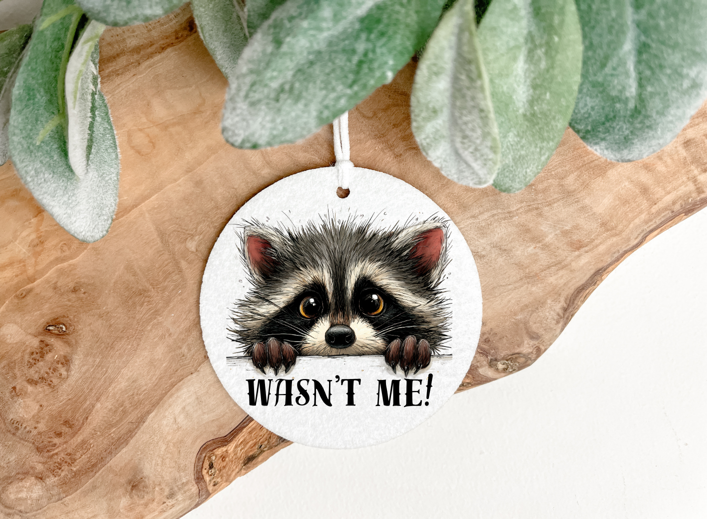 Roundair freshener with  a raccoon illustration and a personalised name text oprinted onto both sides,the airfreshner comes with a random coloured ribbon for hanging